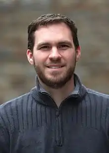 A headshot of Geoff Knorr.  He is wearing a sweater and smiling facing the camera with a blurred background.