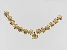 Mycenaean necklace; 1400–1050 BC; gilded terracotta; diameter of the rosettes: 2.7 centimetres (1.1 in), with variations of circa 0.1 centimetres (0.039 in), length of the pendant 3.7 centimetres (1.5 in); Metropolitan Museum of Art (New York City)