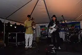 A man playing Sarangi alongside a man playing electric guitar in a concert in Baltimore, USA