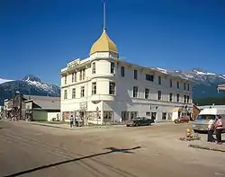 Photograph of the Golden North Hotel in the Skagway Historic District, and other historic buildings, across a broad, unbusy street with dramatic mountains behind.