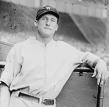 A man wearing a white baseball uniform and dark cap with a white "W" on the face leaning on his left elbow