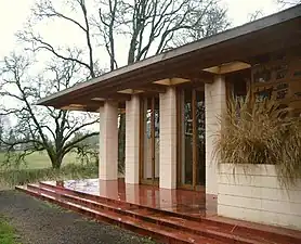 Gordon House living room exterior features 12 foot floor-to-ceiling windows; the steps and foundation replicate the original