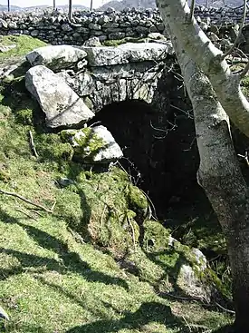 A bridge built from rough rocks. It looks similar to a tunnel.