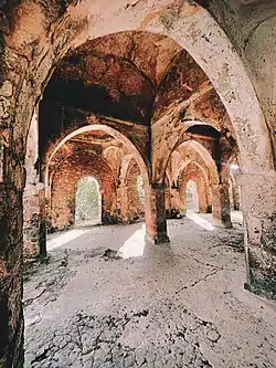 Interior of a mosque in ruins, with vaulted ceiling and bare walls