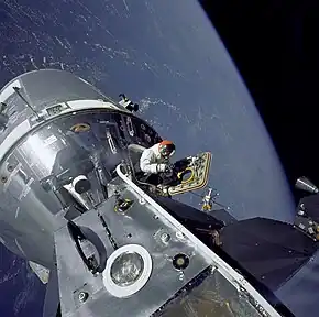 Astronaut halfway out of spacecraft, Earth in background