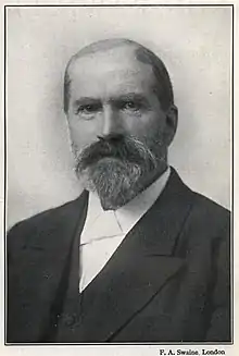 Elderly white man with receding hair and neat beard