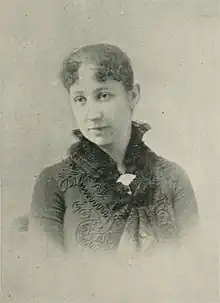 B&W portrait photo of a woman with her hair in an up-do, wearing a dark jacket.