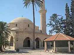 Mosque in stone, a minaret and a shrine in front.