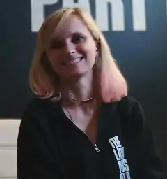 A 33-year-old woman with blonde hair smiling at the camera.