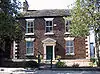 A symmetrical brick house in two storeys with a central pedimented doorway