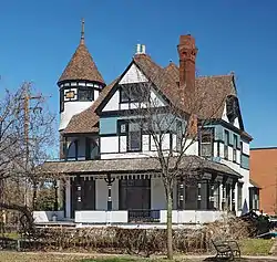 Ornate two-and-a-half-story house with a corner turret, wraparound porch, and complex gabled roof