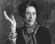 A black-and-white image of an older woman with raised hand