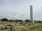 A free standing column and ruins around