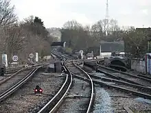 A pair of third-rail railway tracks are intersected by a second pair of tracks coming in from the right