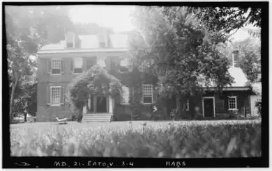 two and a half-story brick house with multiple chimneys and wing on the right