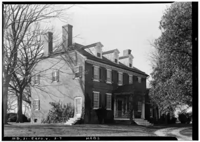 two and a half-story brick house with multiple chimneys and covered front entrance