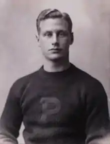 Black-and-white photo of the upper half of a young man wearing a sweater with a large "P" on the front