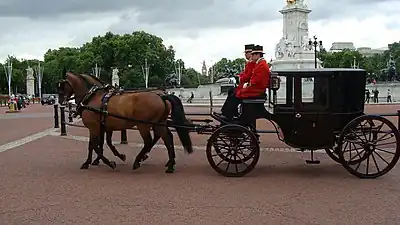 A clarence from the Royal Mews, drawn by a pair of Cleveland Bay horses, passing the Victoria Memorial. (A clarence is a larger-than-standard, two-horse brougham.)