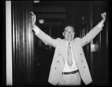 Huey Long standing in a doorway smiling