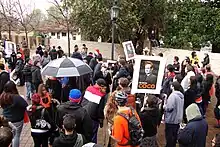 A gathering crowd where some people wear orange and hold signs that say "I'm With Coco".