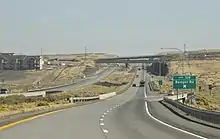 A divided highway approaching a dip in the road and an interchange near several apartment buildings