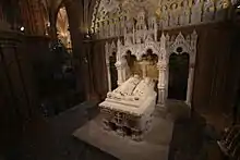 A tomb made of white stone, depicting a man and a woman with lions at their feet