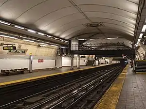 View of the 168th Street station, which has two tracks, two side platforms, and a vaulted ceiling. There are two footbridges linking the platforms.