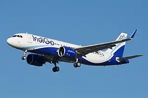 A twin-engined jet aircraft with distinctive winglets, in blue and white livery, against a blue sky