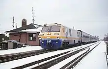 Yellow, blue, and white diesel locomotive with coaches in the snow