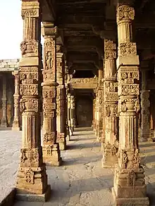 Intricate stone carvings on the cloister columns at Quwwat ul-Islam Mosque, Qutb complex, Delhi. These are recycled Hindu temple pillars displaying Hindu iconography.