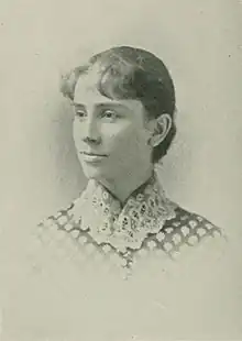 B&W portrait photo of a young woman with hair in an up-do, wearing a checkered blouse with a high-necked white lace collar.