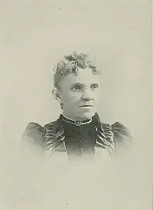 B&W portrait photo of a middle-aged woman with her hair in an up-do, wearing a high-collared dark blouse.