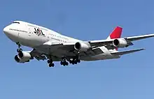 A Boeing 747-400 aircraft in mid-air, with blue sky in the background