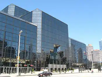 A building of dark tinted glass stands over a city street. The corners of the building are smoothed at 45-degree angles.