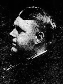 Middle-aged white man in profile; he has short hair, round cheeks, and a heavy brow