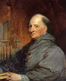 A painting of an elderly, balding, priest wearing a gray robe and a large cross necklace sits, facing left, in front of a brown curtain and bookshelf.