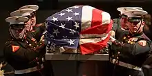 Six marines carrying Glenn's casket, which has an American flag draped around it