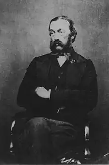 b&w seated portrait photo of a bearded man