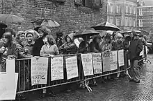 About thirty demonstrators stand behind crowd barriers in the Binnenhof while it is raining. Banners read, among other things, "Don't let the woman end up with the bill" and "No compromises, the woman should decide."