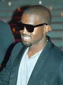 A man wearing a blue T-shirt, a black jacket and sunglasses