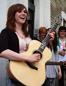 A picture of a smiling woman playing a guitar