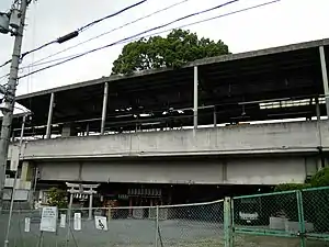 Kayashima Station with the camphor sacred tree growing through it with a shrine at the base