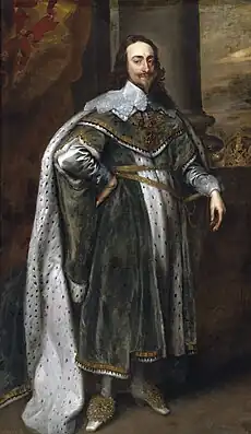 Charles in green robes. The Crown Jewels rest on a table behind him.