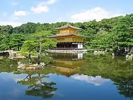 A three storied pavilion. The lower story is in wood and white color, the two upper stories golden.