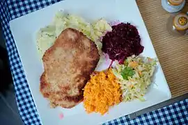 Kotlet schabowy served with potatoes and raw vegetable salads