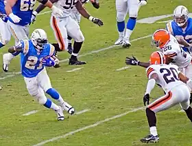 Tomlinson running with the football, attempting to evade two defenders