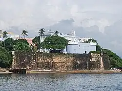 A blue fortress and stone walls above a bay