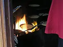 Long-handled skillets over a wood fire