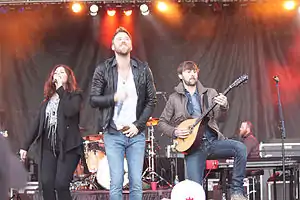 A woman and two men performing music on a stage