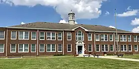 The front facade of a two-story brick building with a white cupola